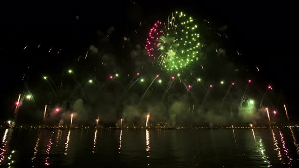 Colorful Fireworks Launched in Air Reflect on Water Surface