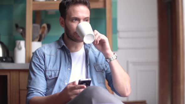 Man relaxing with smartphone and cup of coffee