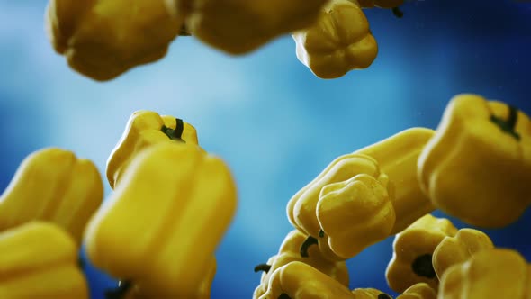 Slow motion animation of natural yellow bell peppers falling down. Loopable. HD