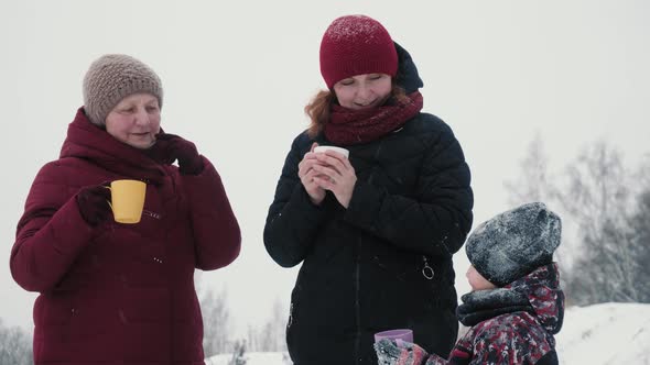 Happy family drinking hot tea outside in winter