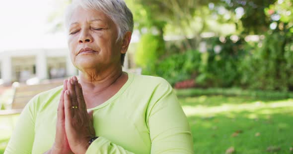 Video of relaxed biracial senior woman practicing yoga in garden