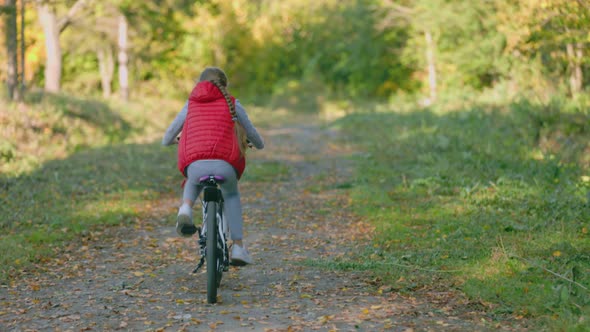 Girl Riding a Bike Near the Forest