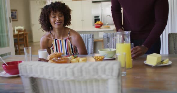 African american family having breakfast sitting together on dining table at home