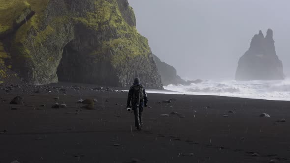 Photographer With Camera In Snow Storm On Black Sand Beach