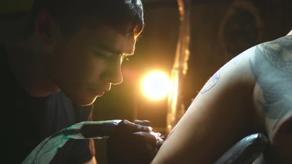 Closeup Portraits of Tattoo Artists Working with Tattooing Machine on Shoulder