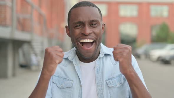 Outdoor Portrait of Excited African Man Celebrating Success