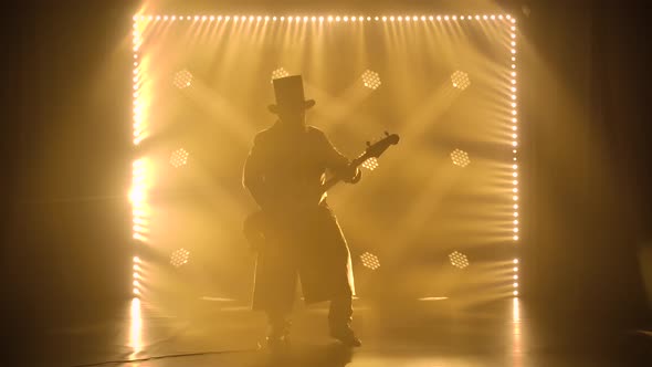An Energetic Performance By a Guitarist in a Dark Smoky Studio with Soft Yellow Light. A Man Plays