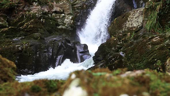 Low Angle View Of Waterfall Cascading Down Rocks In Slow Motion. Slow Slide Left