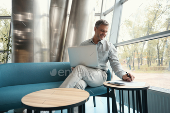project, he sits with laptop in a modern coworking
