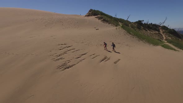 Aerial view of couple hiking on sand dunes at beach