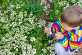 The child looks through a magnifying glass at the flowers Zoom in. - PhotoDune Item for Sale
