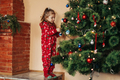 Adorable little girl decorating a Christmas tree with colorful glass baubles at home - PhotoDune Item for Sale