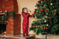 Adorable little girl decorating a Christmas tree with colorful glass baubles at home - PhotoDune Item for Sale