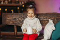 A cheerful baby is drinking hot chocolate on a bench by the fireplace. Christmas mood - PhotoDune Item for Sale