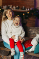 Portrait of a happy little girl sitting on her mother's lap and drinking hot chocolate on Christmas - PhotoDune Item for Sale