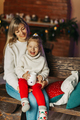 Portrait of a happy little girl sitting on her mother's lap and drinking hot chocolate on Christmas - PhotoDune Item for Sale
