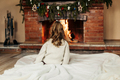 A little girl sits by the fireplace in a cozy living room on Christmas Eve - PhotoDune Item for Sale