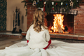 A little girl sits by the fireplace in a cozy living room on Christmas Eve - PhotoDune Item for Sale