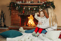 Mother and daughter hugging and warming up on a winter evening by the fireplace for Christmas - PhotoDune Item for Sale