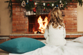 A little girl sits by the fireplace in a cozy living room on Christmas Eve - PhotoDune Item for Sale