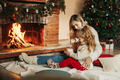 Mother and daughter hugging and warming up on a winter evening by the fireplace for Christmas - PhotoDune Item for Sale