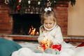 Cute little girl sitting by the fireplace with a Christmas garland.Christmas portrait, cozy style - PhotoDune Item for Sale