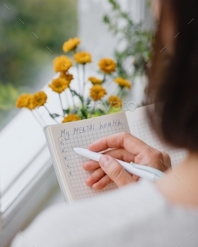 European woman takes care of mental health and writes down the morning pages in a notebook