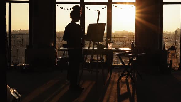 A Figure of Female Artist Shaded By Sunset on Background Drawing on Easel