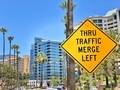 Thru Traffic Merge Left sign on the street by condominium apartment complex buildings & palm trees - PhotoDune Item for Sale