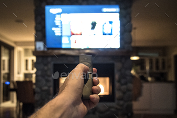 ote control up to control a large television set hanging over a fireplace, foreground focus. RLTheis