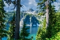 Alpine lake with jagged rock mountain peaks framed by evergreen pine trees. - PhotoDune Item for Sale