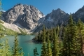 Dramatic landscape alpine lake in evergreen forest surrounded by jagged mountain peaks. - PhotoDune Item for Sale