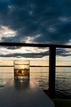 Whiskey on ice drink resting on deck chair arm at sunset by the sea. - PhotoDune Item for Sale