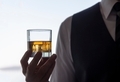 Whiskey on ice drink glass in silhouetted hand at social gathering. - PhotoDune Item for Sale