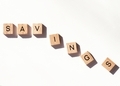 SAVINGS spelled out in wooden letter tiles falling away while being eaten by inflation.  - PhotoDune Item for Sale