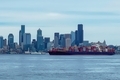 Large cargo container ship full of imports exports with Seattle city skyline on Elliott Bay. - PhotoDune Item for Sale