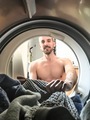 Smiling shirtless man pulling laundry out of dryer.  - PhotoDune Item for Sale