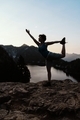 Woman doing a yoga pose in silhouette above mountain lake.  - PhotoDune Item for Sale