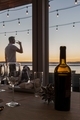 Dinner party table with man in background drinking glass of wine at sunset - PhotoDune Item for Sale