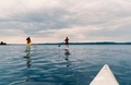 Paddle boarders on placid water under overcast cloudy sky. - PhotoDune Item for Sale
