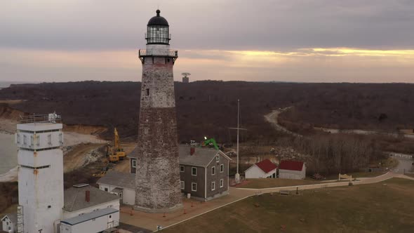 An aerial view of the Montauk lighthouse during a cloudy sunset. The drone camera dolly out and boom