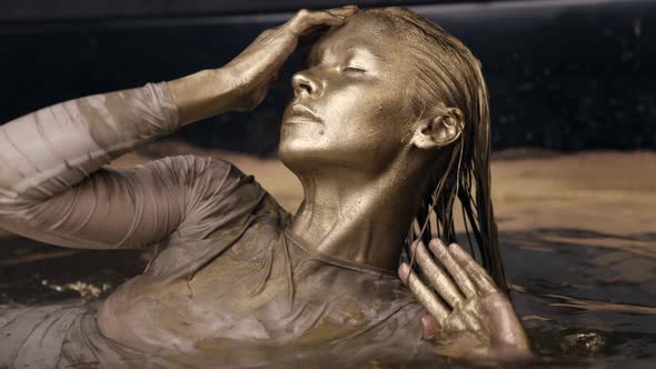 Golden Goddess Is Rising From Water Woman Covered Gold Dye Is Lying in Shallow