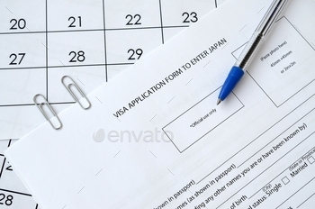 Visa application form to enter Japan and blue pen on paper calendar page close up