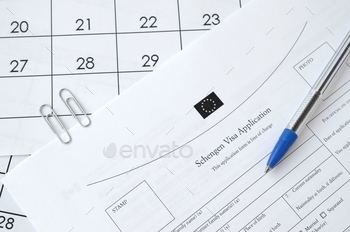 Schengen Visa application form and blue pen on paper calendar page close up