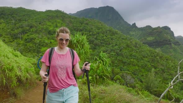 Woman Travels Through a Summer Rainforest with a Backpack and Sticks Hawaii USA