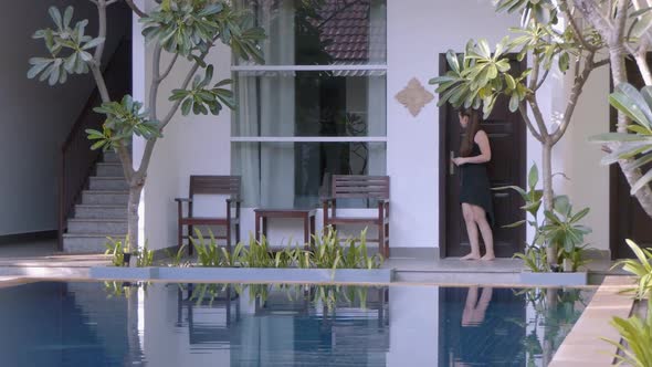 Medium Shot of a Young Lady Leaving her Hotel Room to Sit on the Terrace and Admire the Hotel Ground