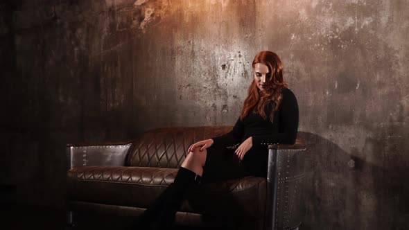 Sweet Lady Elegantly Neatly Sits on the Sofa on a Stylish Wall Background