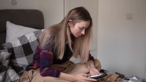 Concentrated Woman in the Morning Sitting in Bed Surfing Internet Using Tablet