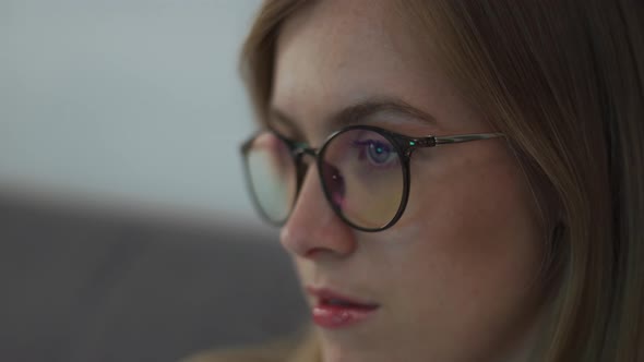 Close up of woman wearing blue light blocking glasses watching TV