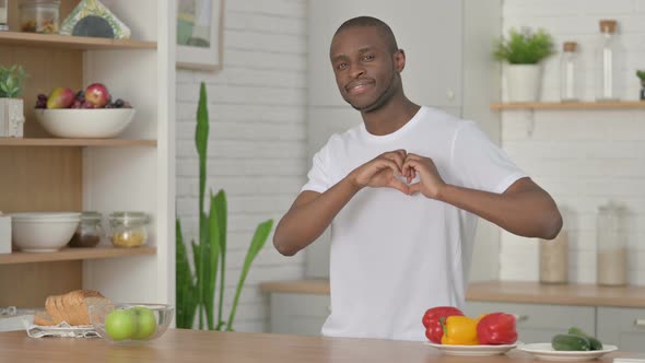 Athletic African Man Making Heart Shape By Hands While in Kitchen